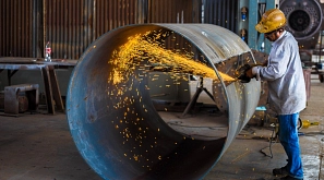 Ein Mann bearbeitet ein Metallrohr mit einer Flex, so dass Funken sprühen