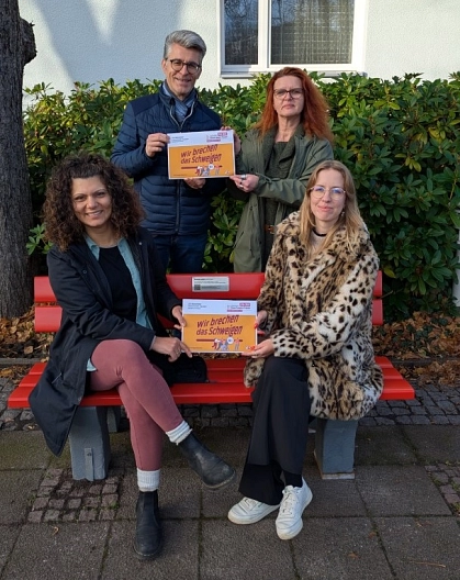 Pegah Metje von der AWO-Frauenberatungsstelle Seelze/Garbsen (vorn, von links) und Seelzes Gleichstellungsbeauftragte Joyce Feig sowie Bürgermeister Alexander Masthoff und Bettina Vorbeck von der Beratungsstelle für Eltern, Kinder und Jugendliche der Region Hannover stellen die rote Bank auf dem Rathausplatz vor.&nbsp;&copy;&nbsp;Stadt Seelze