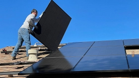 Ein Mann montiert Sonnenkollektoren auf ein Dach